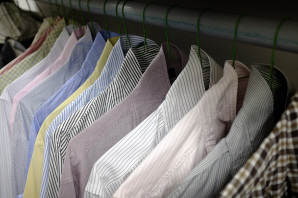 Camisas de vestido penduradas em cabides no armário
 - Foto, Imagem