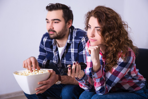 young couple with popcorn watching movie on tv - Fotografie, Obrázek