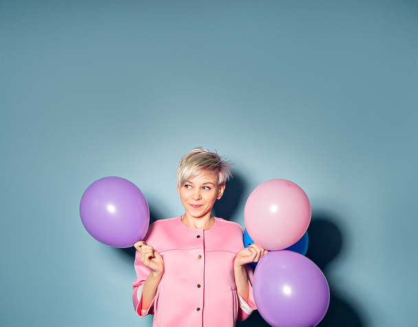 kız mavi arka plan üzerinde renkli balonlar ile iyi eğlenceler - Fotoğraf, Görsel