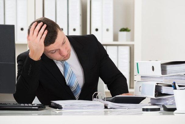 Stressed Accountant Sitting At Desk In Office - 写真・画像