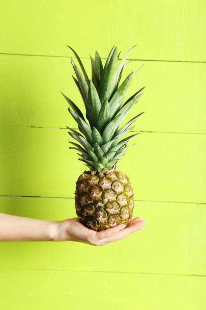 Female hand holding ripe pineapple - Фото, зображення