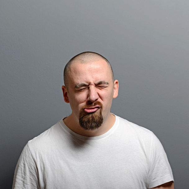 Portrait of a man making funny face against gray background - Foto, imagen