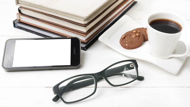 coffee cup with cookie,phone,stack of book and eyeglasses - 写真・画像