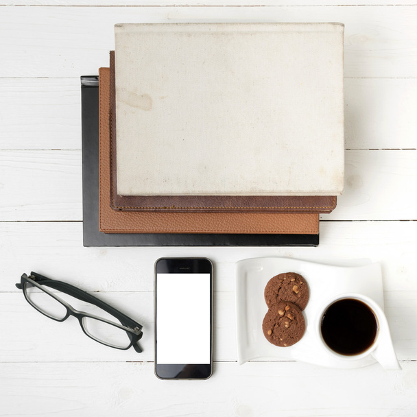 taza de café con galletas, teléfono, pila de libros y anteojos
 - Foto, imagen
