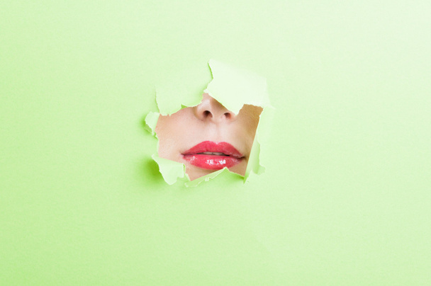 Pretty female mouth wearing lipstick thru ripped paper hole - Zdjęcie, obraz