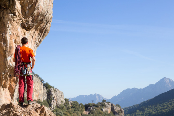 Mladý muž lezení na vápencové zdi se širokým údolím na pozadí - Fotografie, Obrázek