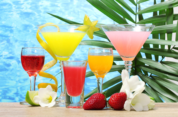 Exotic cocktails and flowers on table on blue sea background - Фото, изображение