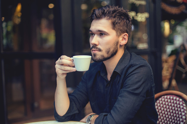 Cutie man with cup of coffee looking at mobile phone outdoors - Fotoğraf, Görsel