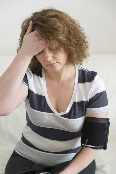 Woman with headache measures a  blood pressure - Photo, Image