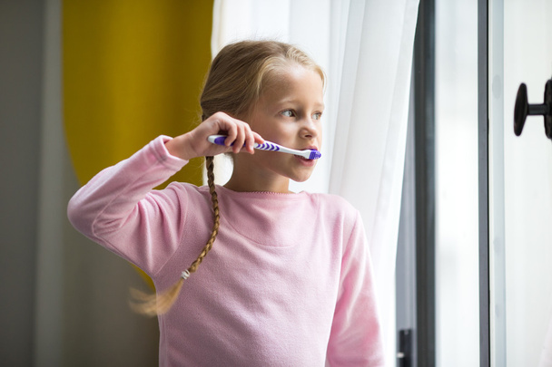 Igiene dentale. Felice bambina lavarsi i denti al coperto
 - Foto, immagini