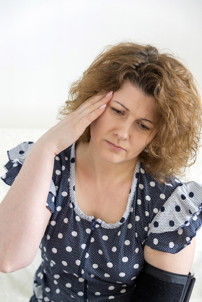 Woman with headache measures blood pressure - Foto, afbeelding