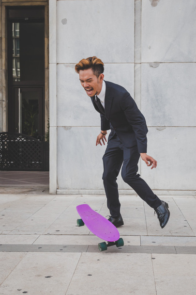 Young handsome Asian model jumping with his skateboard - Φωτογραφία, εικόνα