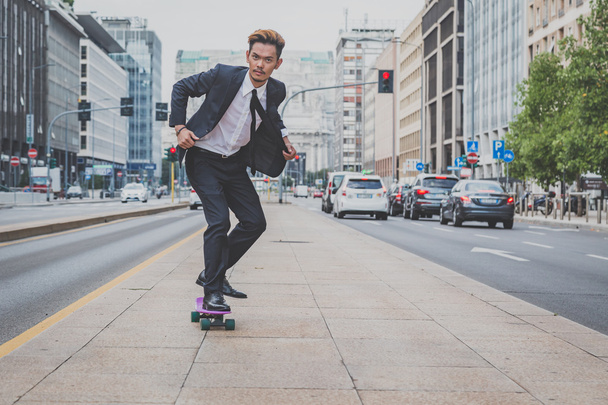 Young handsome Asian model riding his skateboard - Photo, image