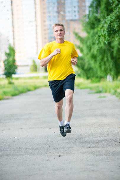 Sporty man jogging in city street park. Outdoor fitness. - Fotó, kép