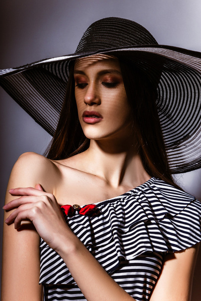 Fashion girl in a big hat in the studio - Фото, изображение