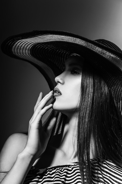 Fashion girl in a big hat in the studio. Black and white - Фото, изображение