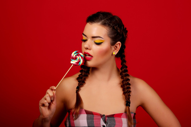 beautiful girl not red background, holding a candy - Foto, imagen