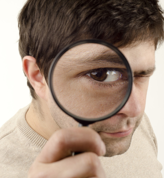 Young man looking throught magnifying glass - 写真・画像