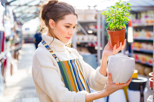 Thoughtful woman gardener choosing new pot in store - Zdjęcie, obraz