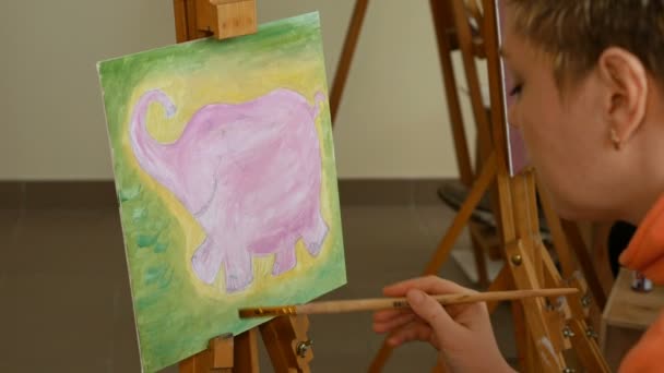 Naistaiteilija maalaa kuvataidetta taidestudiossa
 - Materiaali, video