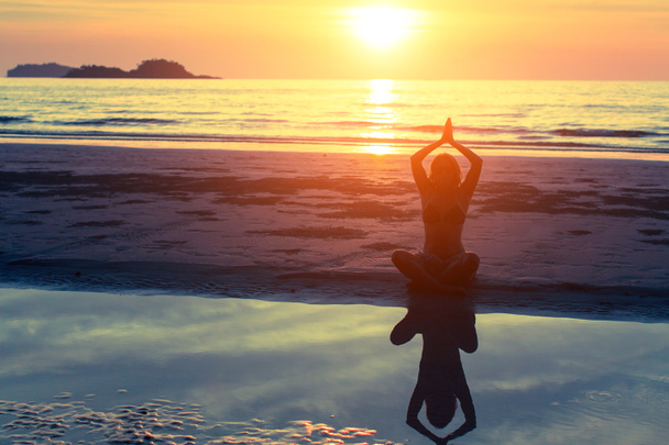 vrouw oefenen yoga op het strand - Foto, afbeelding