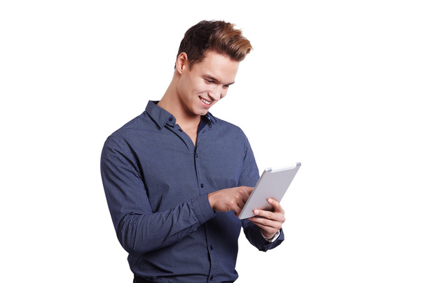 Smiling young man using tablet computer against a white background - Fotó, kép