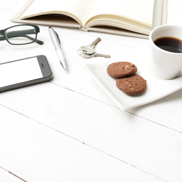 coffee cup with cookie,phone,open notebook,key and eyeglasses - Фото, изображение