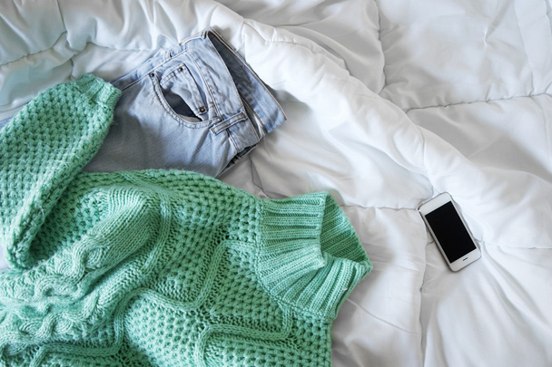 Tenue féminine et smartphone disposés sur le lit, lumière du matin
 - Photo, image