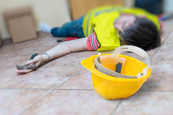 Work injury concept. Worker had an accident and is lying injured on the floor. - Photo, Image