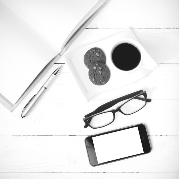 coffee cup with cookie,phone,notebook and eyeglasses black and w - Zdjęcie, obraz