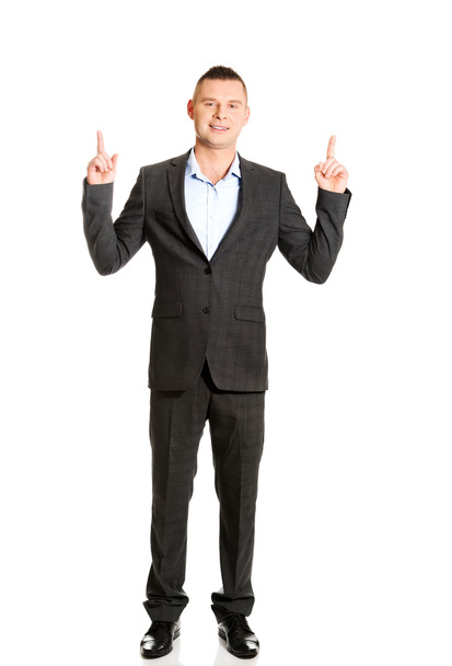 Young businessman pointing upwards - 写真・画像