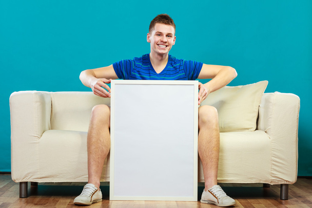 man on sofa holding blank presentation board - Fotografie, Obrázek