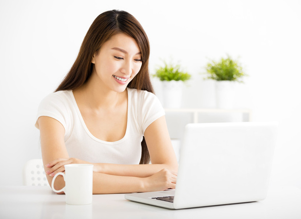 happy young woman with laptop in living room - Фото, изображение