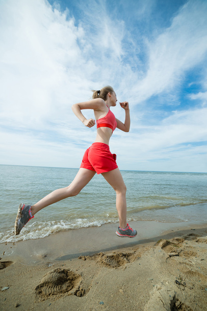 日当たりの良い夏の砂のビーチで実行している若い女性。ワークアウト。ジョギング - 写真・画像