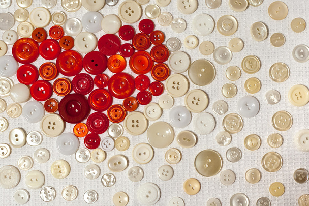 Colorful buttons in shape of heart on white fabric - Photo, Image