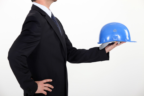 Architect in profile holding out hard hat - Foto, Bild