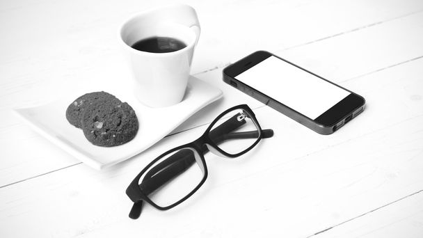 coffee cup with cookie,phone and eyeglasses black and white colo - 写真・画像