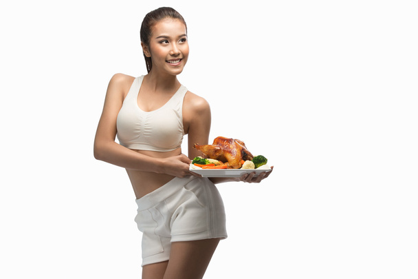 Mujer joven con cuerpo perfecto sosteniendo y mostrando pollo asado para delicioso menú, comida saludable - concepto de estilo de vida saludable
 - Foto, imagen