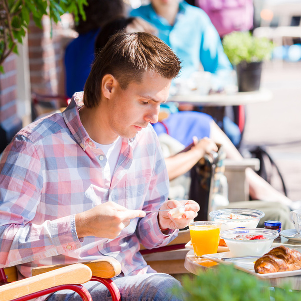 Hombre joven desayunando en la cafetería al aire libre en la ciudad europea
 - Foto, imagen