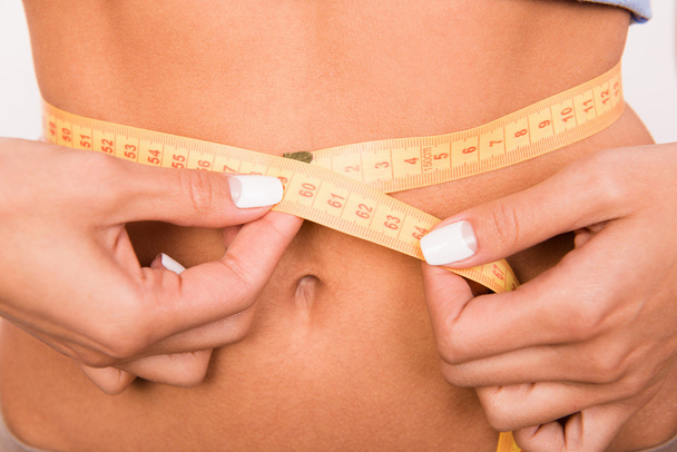 Close up photo of girl's waist with a measuring tape - Foto, Imagen