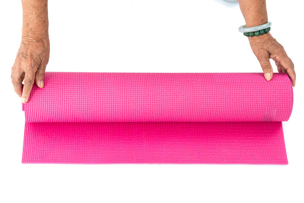 Senior hand's rolling pink yoga mat on white. - Φωτογραφία, εικόνα