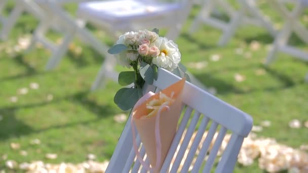 λευκές καρέκλες στο γρασίδι με λουλούδι - Πλάνα, βίντεο