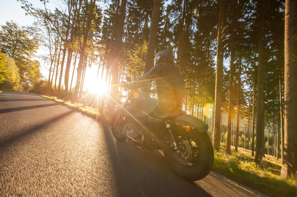 Hombre asiento en la motocicleta en el camino del bosque
. - Foto, Imagen