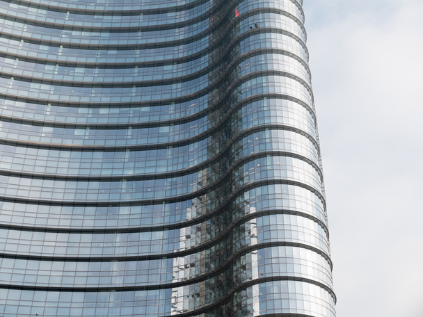Acercamiento arquitectónico del rascacielos moderno de oficinas de gran altura con fachada de vidrio curvado y reflexión de construir en un día soleado con cielo nublado
 - Foto, imagen