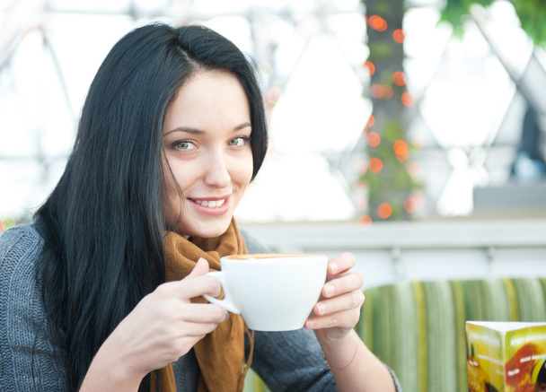 カフェで休憩中のコーヒーのカップを持つかなり若い女性のクローズ アップの肖像画 - 写真・画像