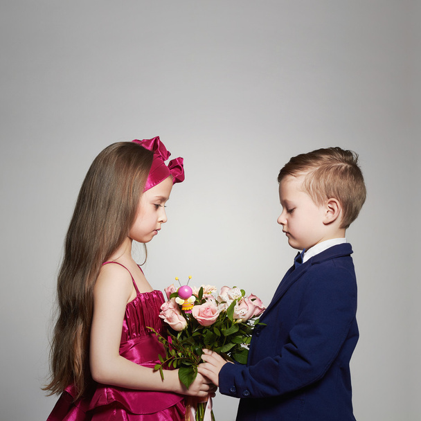 boy gives a girl flowers.little beautiful couple.kids love,roses bouquet - Fotó, kép
