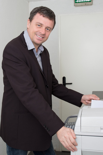 Charmant homme utilisant une photocopieuse au travail
  - Photo, image