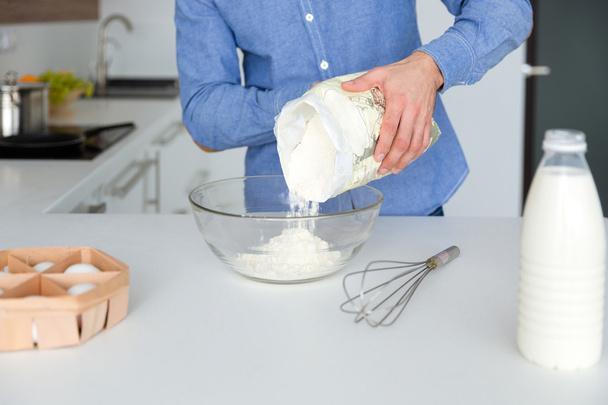 Closeup of man in blue shirt preparing dough on kitchen  - Fotó, kép