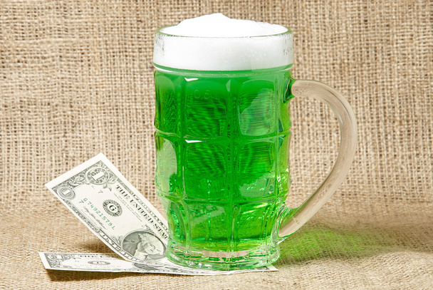Ποτήρι ιρλανδικό πράσινο μπύρα και δολάρια σε φόντο λινάτσα - Φωτογραφία, εικόνα