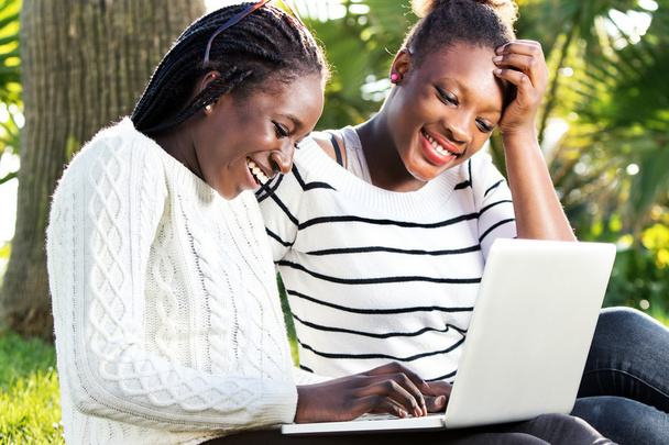 Afrikalı kızlar eğleniyor laptop Park. - Fotoğraf, Görsel